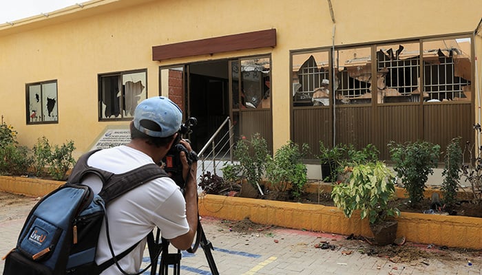 A cameraman films broken glass windows at the district Malir Jail, after dozens of prisoners escaped from the jail, on the outskirts of Karachi, June 3, 2025. — Reuters