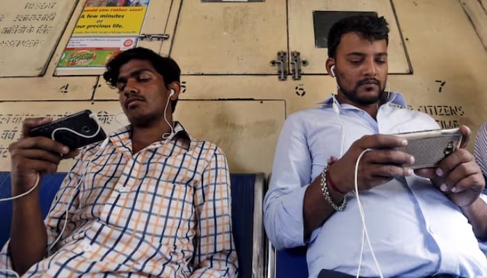 Commuters watch videos on their mobile phones as they travel in a suburban train in Mumbai, India, on April 2, 2016. — Reuters
