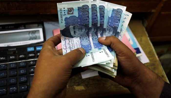A trader counts Pakistani rupee notes at a currency exchange booth in Peshawar, Pakistan December 3, 2018. — Reuters
