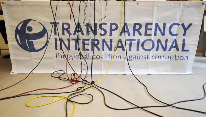 Microphone cables dangle over a logo of Transparency International. — AFP