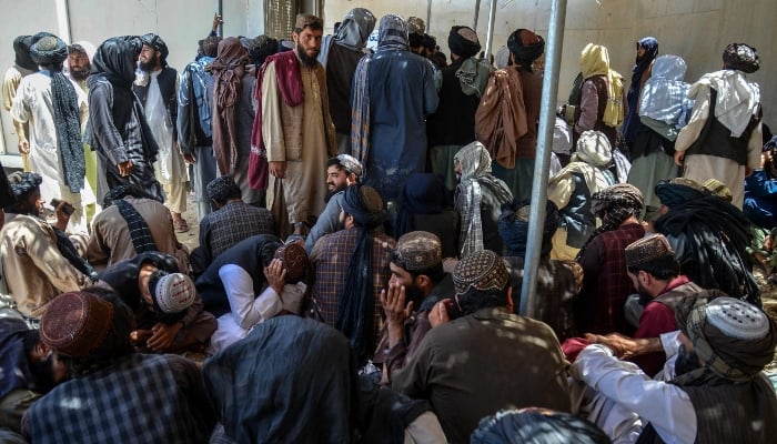 Taliban government employees wait to receive their salaries as they gather outside the New Kabul Bank in Kandahar on June 2, 2025. — AFP