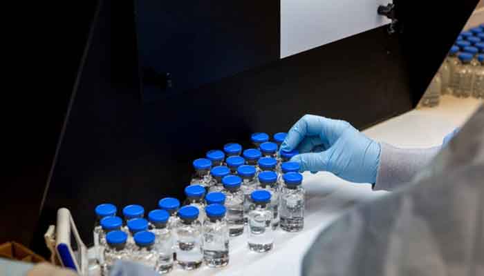 A lab technician inspects filled vials of drug. — Reuters/File