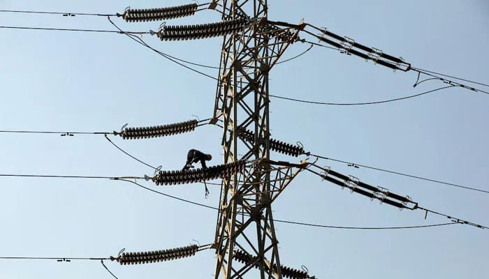 A technician works on porcelain insulators on power transmission tower in Karachi. — Reuters/File
