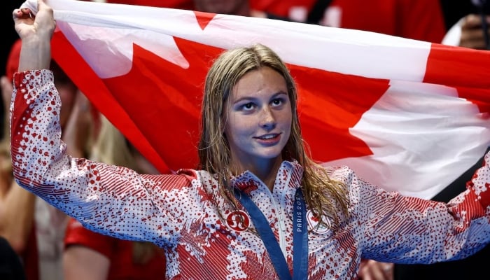 Gold medallist Summer McIntosh of Canada celebrates holding a flag after winning Womens 400m Ind. Medley, Paris La Defense Arena, Nanterre, France, July 29, 2024. — Reuters