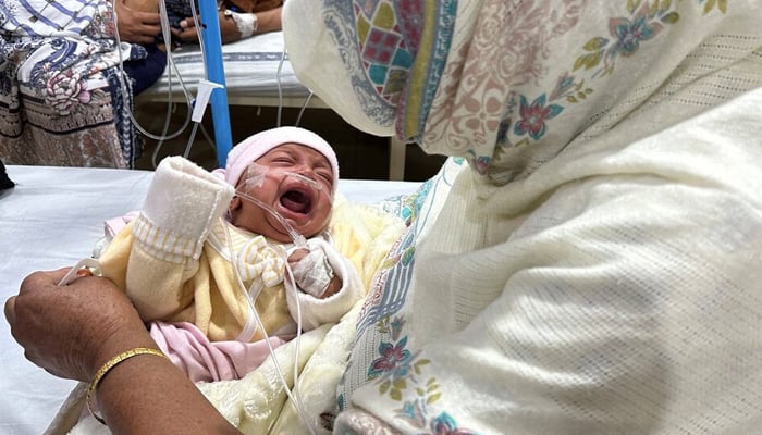 A baby girl cries while being comforted by her grandmother inside the paediatric ward at Sir Ganga Ram Hospital where she is being treated for pneumonia amidst soaring air pollution in Lahore, Pakistan, December 4, 2023. — Reuters