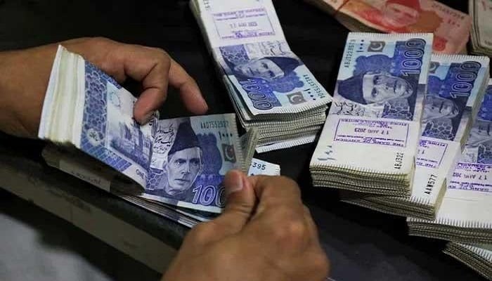 An employee counts Pakistani rupee notes at a bank in Peshawar. — Reuters/File