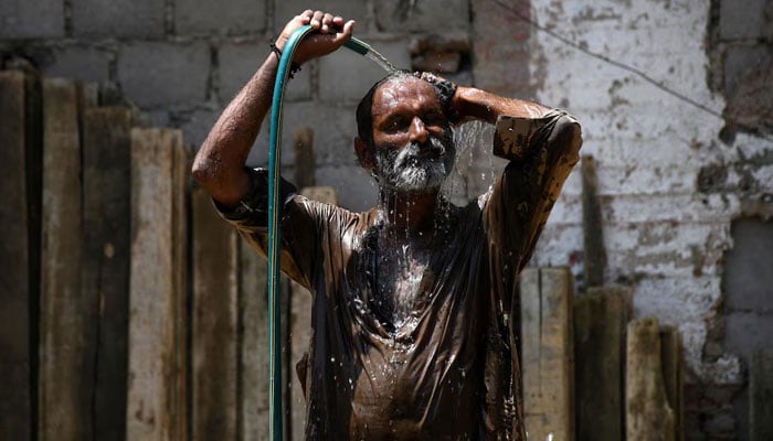 A man cools off with a water hose during a hot summer day in Hyderabad on May 24, 2024. — Reuters