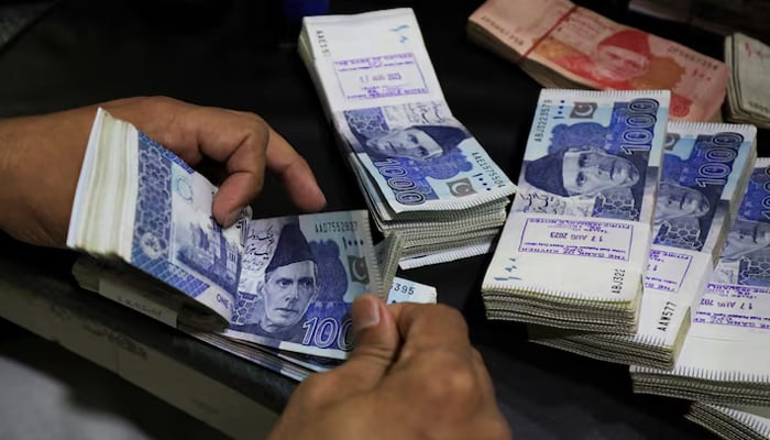 An employee counts Pakistani rupee notes at a bank in Peshawar on August 22, 2023. — Reuters