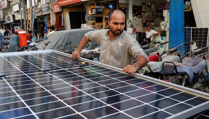 A worker loads solar panels on a vehicle, outside a shop at a market selling electronic items in Karachi, June 11, 2024. — Reuters