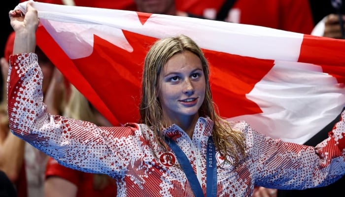 Olympic gold medallist Summer McIntosh of Canada celebrates holding a flag after winning Womens 400m Ind. Medley, Paris La Defense Arena, Nanterre, France, July 29, 2024. — Reuters