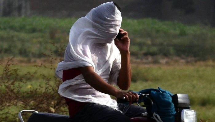 A motorcyclist on the way covered his face withy wet cloth piece to protest from heat waves in Lahore, June 10, 2025. — INP