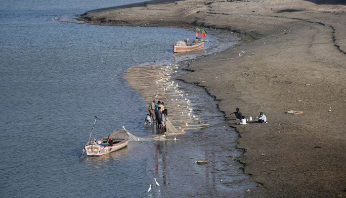 Fishermen clear a fishing net in the water on the partially dried up riverbed of the Indus River in Hyderabad on April 25, 2025. — Reuters