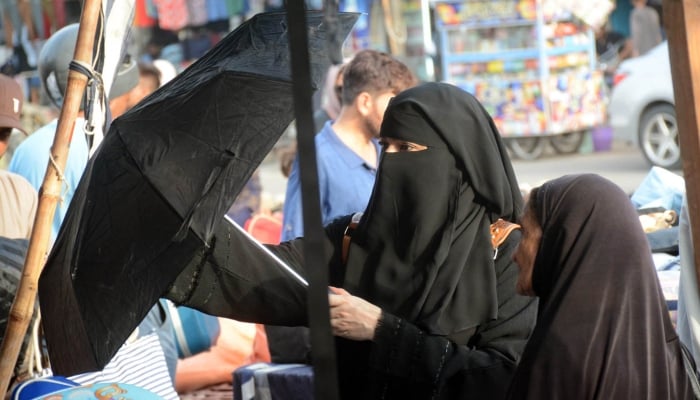 Women purchasing a parasol  from a vendor to protect themselves from scorching heat.