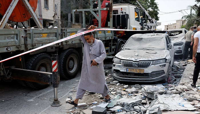 A man walks near damaged vehicles and debris after missiles fired from Iran impacted on a residential building in northern Israel, in Tamra, Israel, June 15, 2025. — Reuters