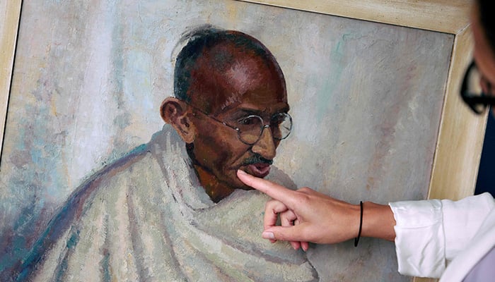 Rhyanon Demery, Bonhams Head of Sale for Travel and Exploration, points out the spot where the now-restored painting by British-American artist Clare Leighton of Indian independence leader Mahatma Gandhi was once damaged at Bonhams auction house in London on June 9, 2025. — AFP