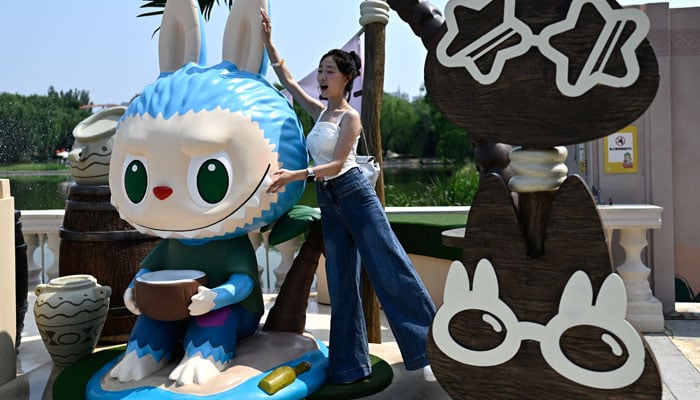 A woman poses for a picture next to the character Labubu as she visits Pop Mart theme park Pop Land in Beijing, China on June 18, 2025. — AFP