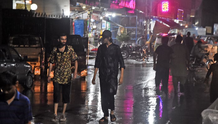 People make their way along a road as heavy rain lashes Rawalpindi on June 22, 2025. — Online