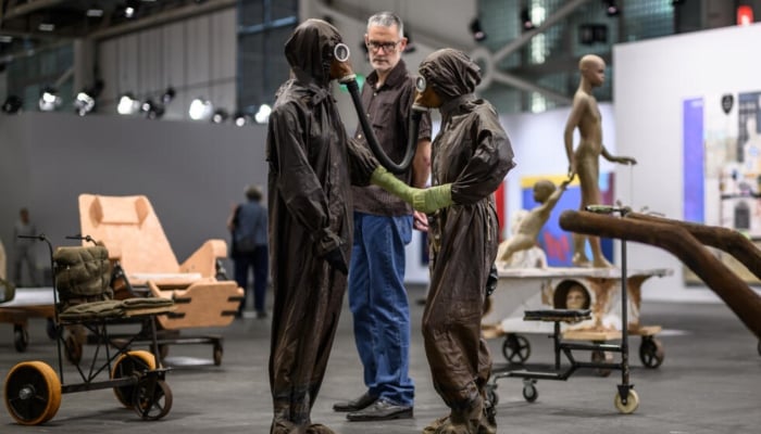 An Art Basel visitor has a close look at part of The Voyage — A March To Utopia, by Atelier Van Lieshout. — AFP/ File