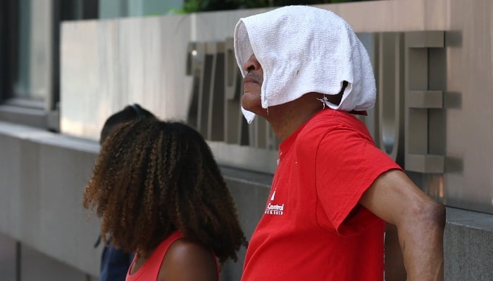 A man stands with a towel on his head in midtown Manhattan on June 23, 2025 after an excessive heat warning was issued for the New York City area. — AFP