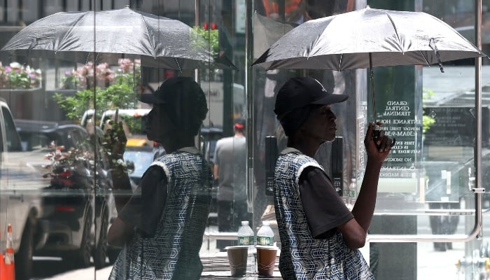 A person stands with an umbrella in midtown Manhattan on June 23, 2025 after an excessive heat warning was issued for the New York City area. — AFP