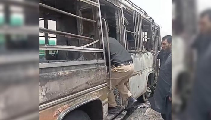 A policeman inspects the charred remains of a bus which caught fire on the western bypass in Balochistan. — Reporter