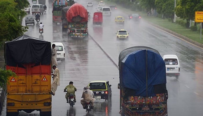 Commuters and vehicles pictured in Islamabad during rain. — AFP/File