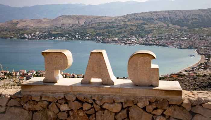 This photograph shows a stone inscription reading PAG at a viewpoint overlooking the city of Pag, Croatia, on June 11, 2025. — AFP