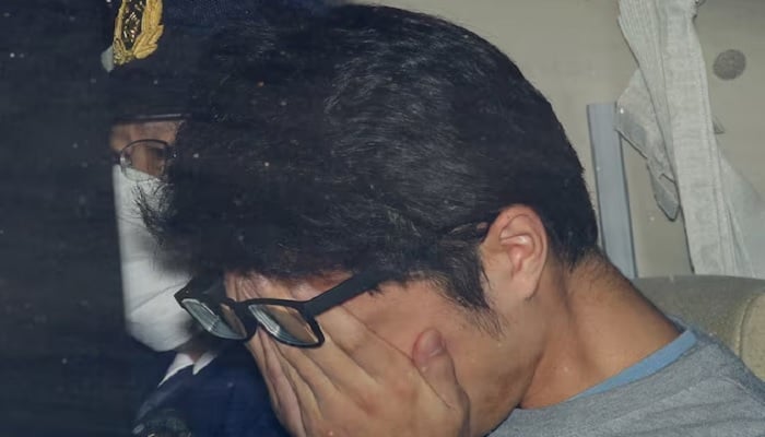 Takahiro Shiraishi covers his face inside a police car in Tokyo, in this photo taken by Kyodo in November 2017 and released by Kyodo on December 15, 2020. — Reuters