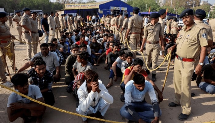 Police officers stand next to men they believe to be undocumented Bangladeshi nationals after they were detained during raids in Ahmedabad, India, on April 26, 2025. —Reuters