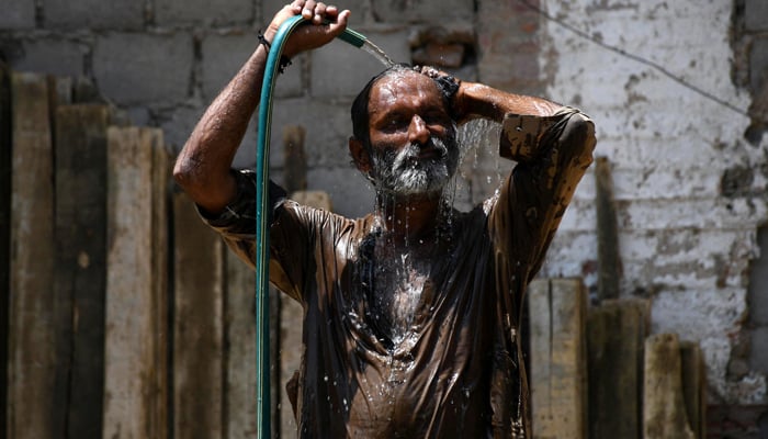 A man cools off with a water hose during a hot summer day in Hyderabad, May 24. — Reuters