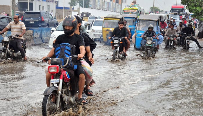 Commuters face difficulties in transportation due to stagnant rainwater after heavy rains during monsoon season, at Qayyumabad area on June 27, 2025. — Online