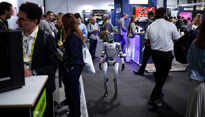 A humanoid robot walks among visitors during the ninth edition of the AI summit London, in London, on June 11, 2025. — AFP