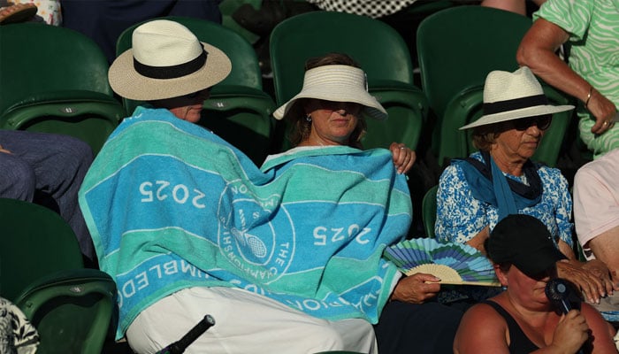 Spectators wear a towel in the stands during the first round match between Italys Jasmine Paolini and Latvias Anastasija Sevastova at the All England Lawn Tennis and Croquet Club in London, Britain on June 30, 2025 . — Reuters