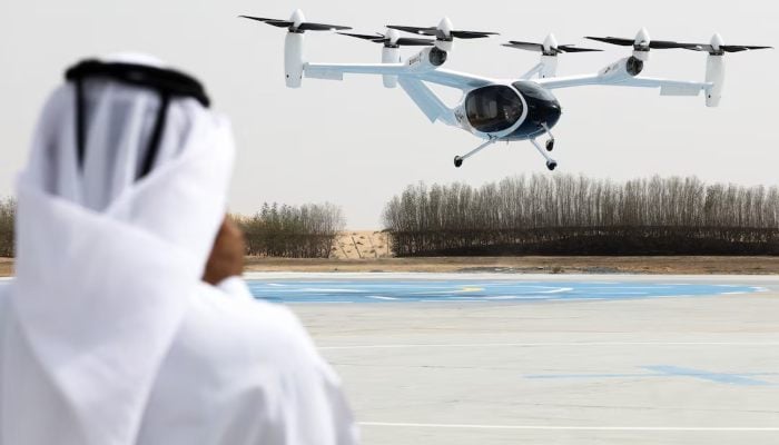 A man wearing traditional Emirati clothes films an experimental Joby Dubai Aerial Taxi aircraft taking off in Dubai, United Arab Emirates, June 30, 2025. — Reuters