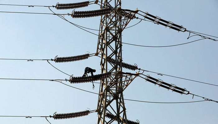 A technician works on porcelain insulators on power transmission tower in Karachi. — Reuters/File