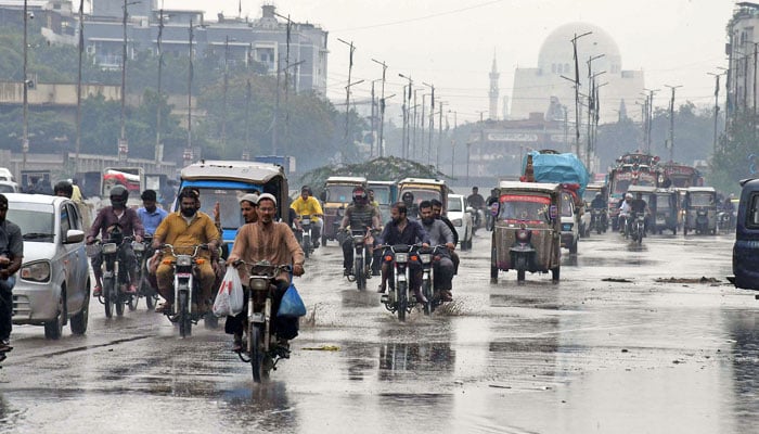 People can be seen driving different vehicles on a wet road during heavy rain in Karachi on June 27, 2025. — Online