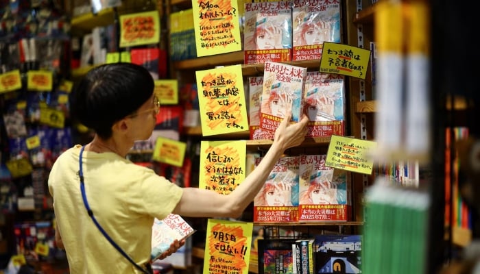 A member of staff places the comic book titled The Future I saw, authored by manga artist Ryo Tatsuki, on the shelf at Village Vanguard book store in Tokyo, Japan, on June 30, 2025. — Reuters