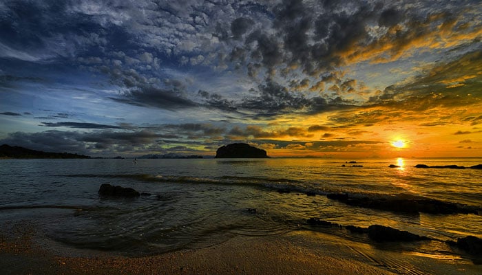 This representational image shows the sun setting over a beach. — Unsplash