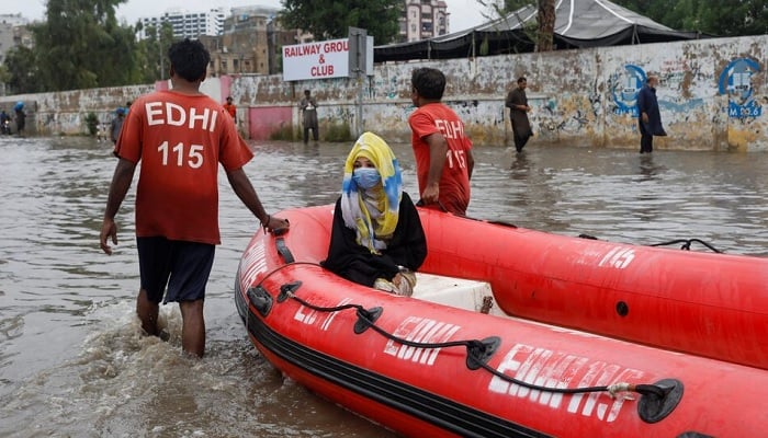A woman sits in a rubber boat as volunteers pull through a flooded road during the monsoon season in Karachi, July 9, 2022. —Reuters