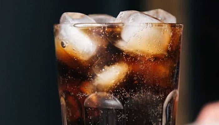 This image shows a gloss full of a soft, sugary beverage. — Pexels