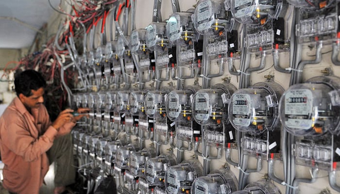 A technician fixes new electricity meters at a residential building in Karachi, on May 13, 2010. — AFP
