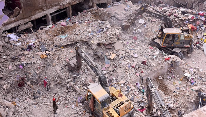 Rescue workers busy in operation at the collapsed building site in Baghdadi, Lyari, as more bodies are recovered from the debris. — APP/File