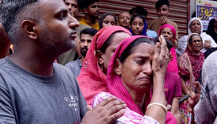 Grief-stricken family members break down in tears at the tragic site of a collapsed residential building in Baghdadi, Lyari. — APP/File