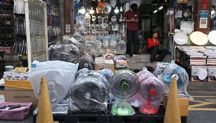 Store workers wait for customers behind a row of fans for sale to combat the heat at an electrical appliances store in Bangkok, Thailand. — AFP/File