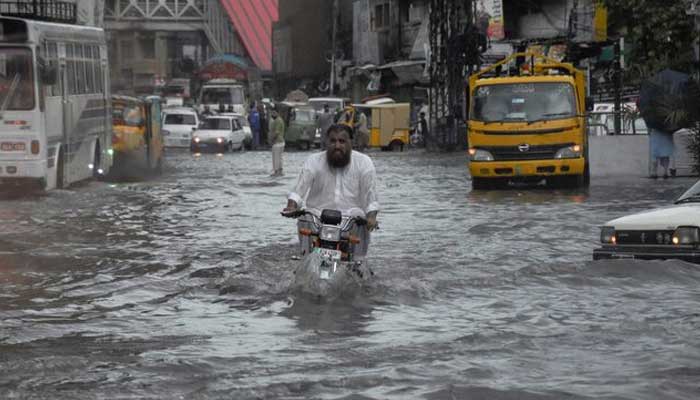 A man rides on a motorcycle amid flood waters along a road during the monsoon season in Rawalpindi. — Reuters/File