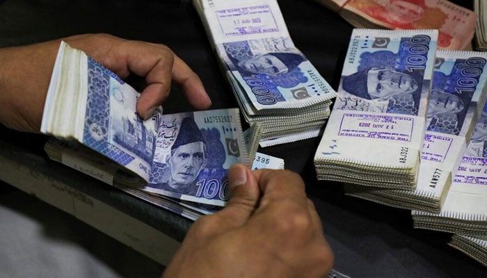 An employee counts Pakistani rupee notes at a bank in Peshawar on  August 22, 2023. — Reuters