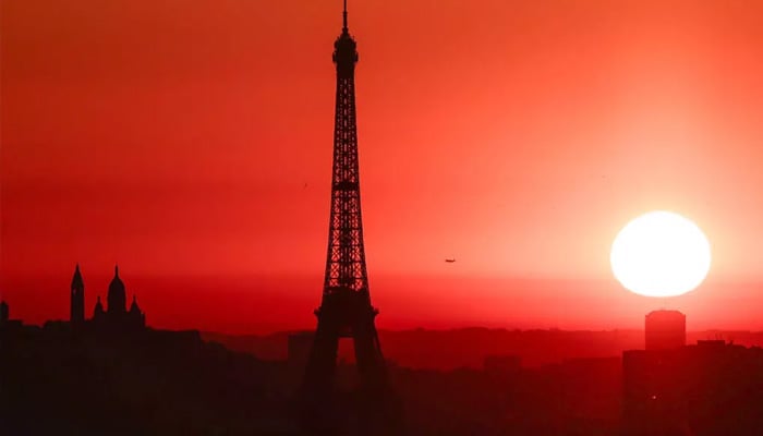 Eiffel Tower silhouetted against glowing sun on a hot summer evening in Paris in this undated image. — AFP