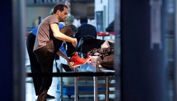 An airline passenger removes his shoes before going through a security check point at JFK Airport in New York. — Reuters