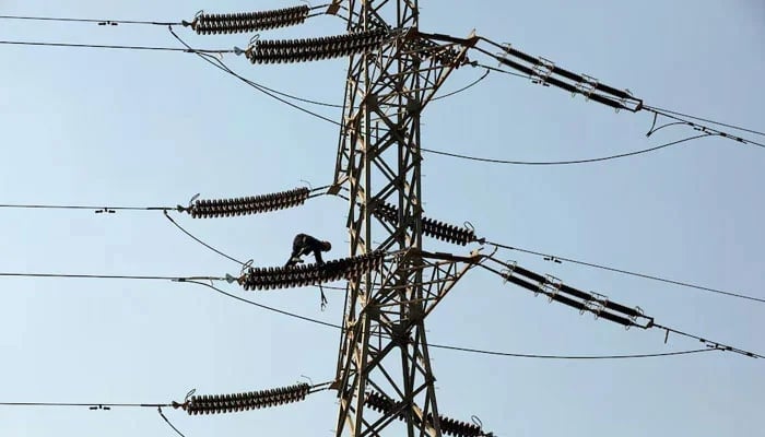 A technician works on porcelain insulators on power transmission tower in Karachi. — Reuters/File