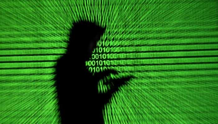 Silhouette of mobile device user is seen next to a screen projection of binary code are seen in this picture illustration taken March 28, 2018. — Reuters